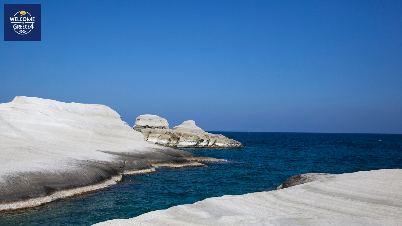 White rocky cliffs and sea waves under a clear blue sky.